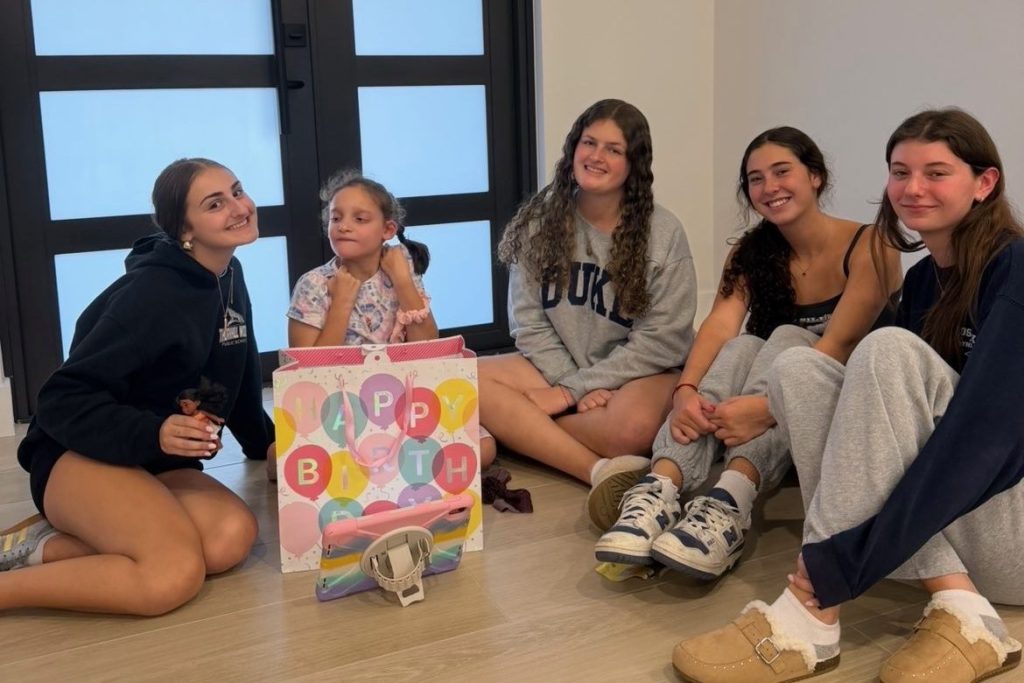 Friendship House teen volunteers sitting with a birthday girl and her gift during a Brighter Birthdays home visit
