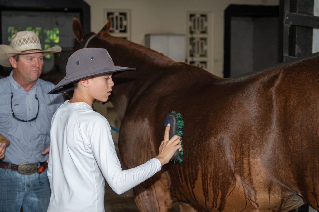 Teen with special needs grooming a horse with an instructor at Equine Connection, Delray Equestrian Center