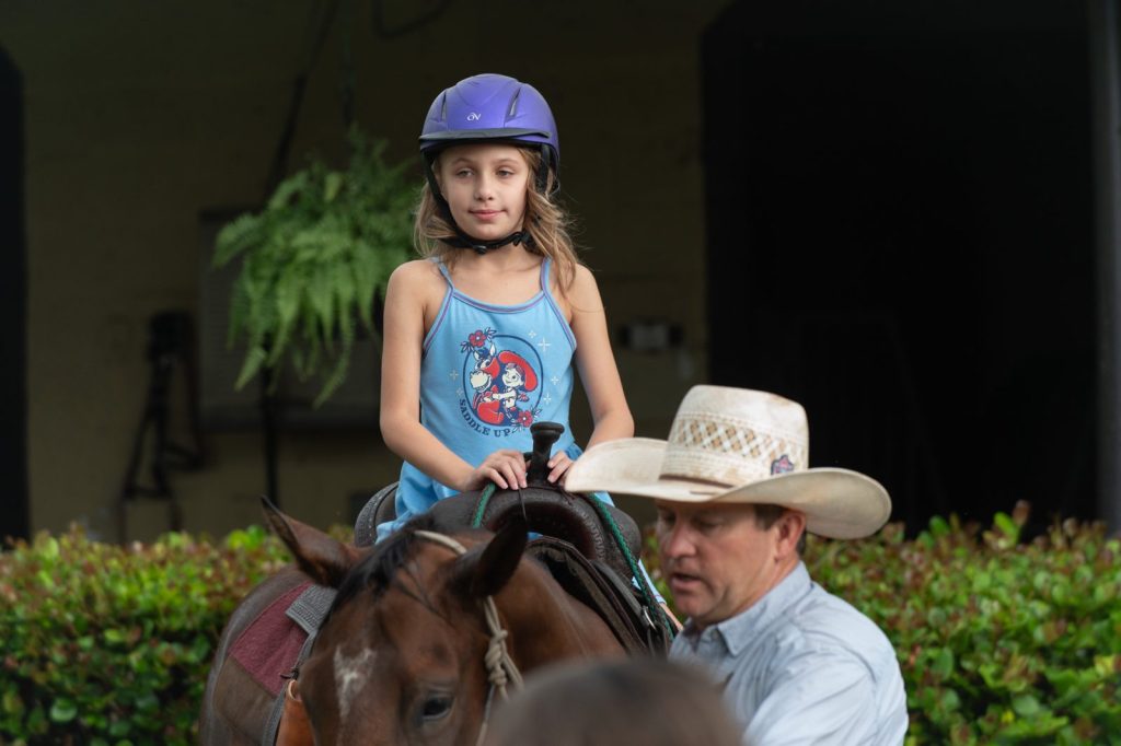 Smiling girl in a riding helmet on horseback at Friendship House Equine Connection